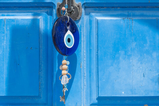 The evil eye souvenir hanging on the Greek door. Blue stone amulet in form of eye to protect from evil people. Nisyros island, Greece