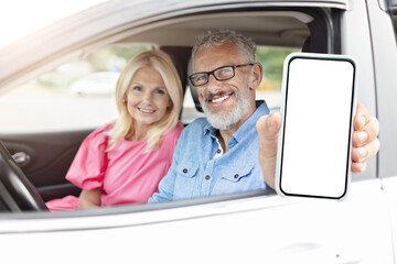 Senior couple in car showing digital device