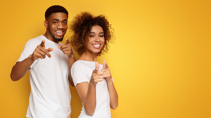 Joyful young couple pointing fingers at camera