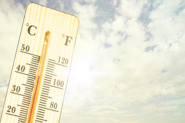 A thermometer on a sunny day with a sunny landscape in the background. climate change and...