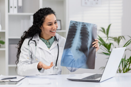 A cheerful female radiologist analyzes a chest X-ray in her medical office, discussing findings and diagnostics with a patient virtually.