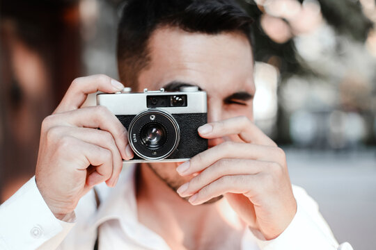 a young man takes photos in the city with his antique photo camera