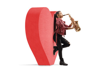 Full length profile shot of a young female saxophonist leaning on a red heart