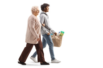 Young african american man walking with an elderly caucasian woman and carrying grocery bags - Powered by Adobe