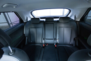 Luxury car rear leather seats row. Interior of new modern clean expensive car. Passenger seats with leather. Closeup details. New electric car inside. Car cleaning theme