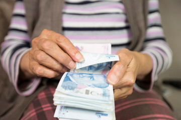 Closeup of wrinkled hands holding turkish lira banknotes  