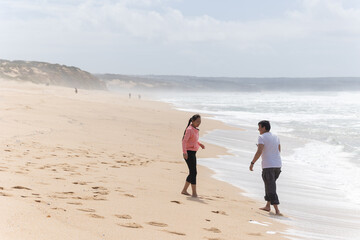 A man and a woman are walking on the beach