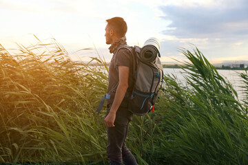 A man is walking through a field with a backpack on. Scene is peaceful and serene, as the man is...