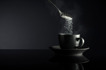 Sugar is poured into a cup of coffee.