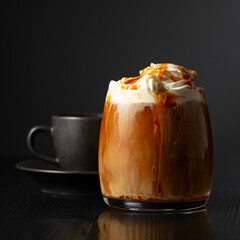 Iced coffee with whipped cream and caramel sauce and cup of black coffee.
