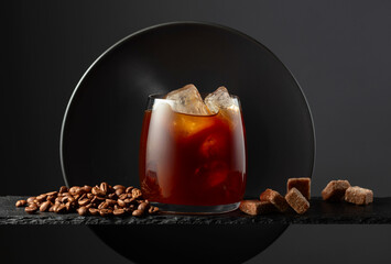 Black coffee with ice on a black background.