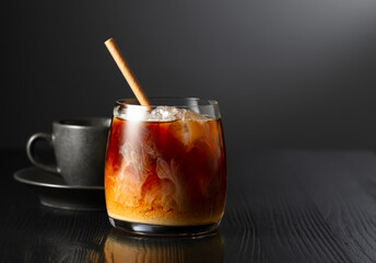 Iced coffee with cream and cup of black coffee on a black wooden table. - 785702715