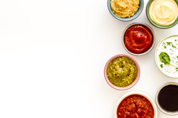 Set of bowls with sauces pesto salsa mustard and others, top view. Food background