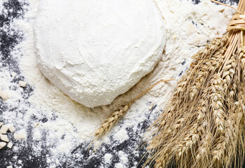 Raw dough flour and ears of wheat on black background top view Home baking concept
