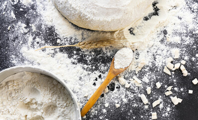 Raw dough flour and ears of wheat on black background top view Home baking concept
