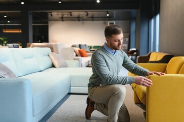 Young man buying sofa in furniture store