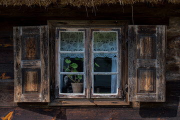 Fototapeta na wymiar drewniane okno w starej drewnianej chłopskiej chacie na wsi