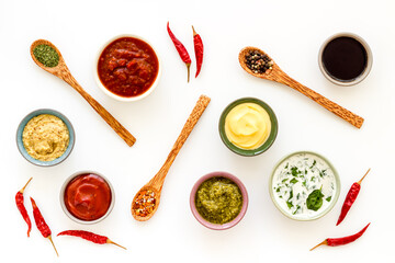 Set of sauces in bowls with spices in spoons and ingredients, top view