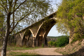 Stone and concrete arched road bridge over the river and hiking trail