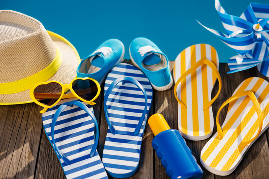 Beach flip-flops and sunglasses on wooden planks near swimming pool
