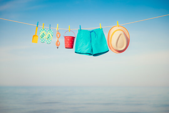 Beach hat, flip-flops and goggles hanging on a clothesline against sea and sky