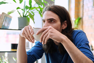 Close up of young handsome man holding drinking cup of coffee