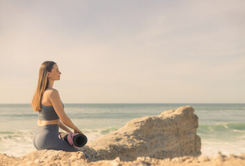A girl is preparing to practice outdoor yoga on the ocean. Calmness and relax. Background with ocean view and yoga trainer. - 785720186