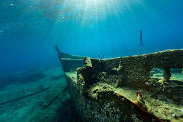 Freediver Swimming in Deep Sea With Sunrays. Young Man Diver Eploring Shipwreck
