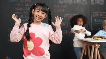 Girl smile and wave to camera while friend working or learning engineering code or prompt in STEM...