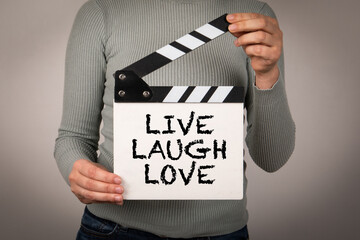 Live Laugh Love. Female hands holding movie clapper - 785722375