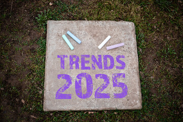 TRENDS 2025. Colored pieces of chalk on a concrete pavement slab - 785722548