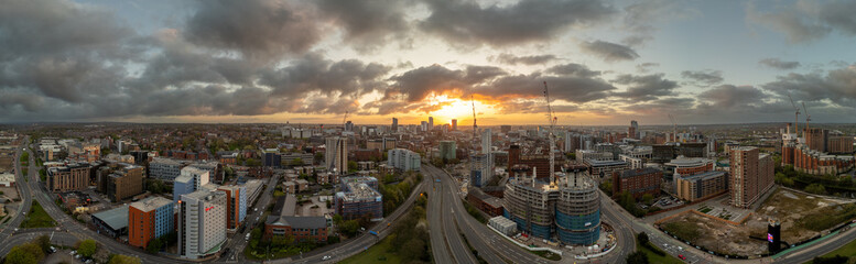Fototapeta na wymiar A beautiful drone photograph of Leeds, West Yorkshire showcasing the sprawling city centre at sunrise with ongoing construction projects and the majesty of building silhouettes