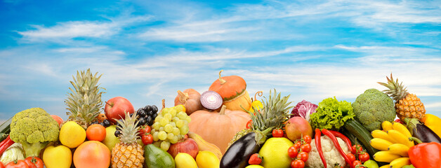 Panoramic photo fruits and vegetables on background clouds and blue sky.