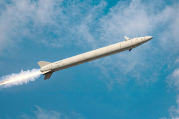A large military ballistic rocket is flying through the blue sky. War concept