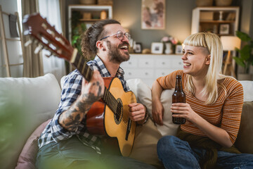Adult couple enjoy at home play guitar and drink beer happy together