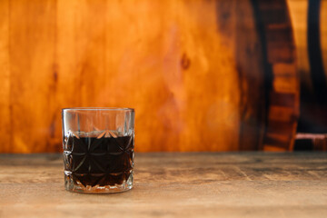 A glass of homemade dark red wine. Wine cellar and oak barrel