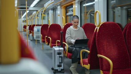 Trendy freelancer working train looking on laptop screen. Informal woman typing