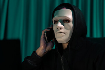 White criminal anonymous mask calling to IT owner to threaten ransom with big database, installing...