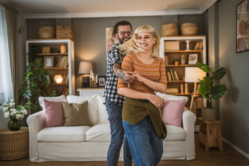 One adult couple dance together and have fun at living room at home