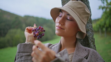 Closeup woman eating grape at autumn vineyard. Portrait of girl enjoying taste 