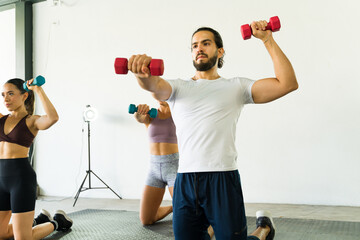 Focused group exercising with dumbbells in fitness studio