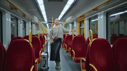 Glamorous woman standing train with luggage. Posh short hair model posing wagon