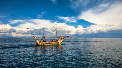 Lake Titicaca, a traditional boat sailing on the blue lake under a cloudless sky