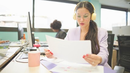 Slow motion of a Young caucasian woman working concentrated in an office with headphones