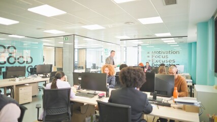 Busy office with diverse employees working and motivational décor.