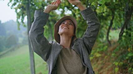 Woman enjoy rainy vineyard closeup. Smiling girl walking between green vine rows