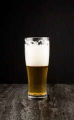 A glass of craft light beer on a dark background. The concept of brewing.
