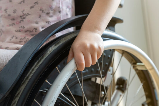 Close-up of a child's hand on the wheel of a wheelchair. The concept of a person with a disability.
