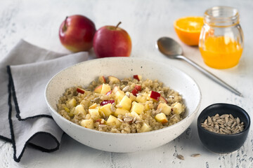 Quinoa with apples, sunflower seeds, honey and orange juice on a light blue table. Vegan healthy dish - 785744765