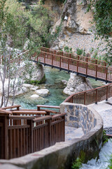 Wooden bridge crossing a crystal clear mountain stream in spain, an idyllic spot for nature walks and reflection.
